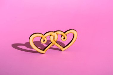 Pembe arka planda tahta çift kalp. Sevgililer gününü fotokopi aletiyle kutluyoruz..