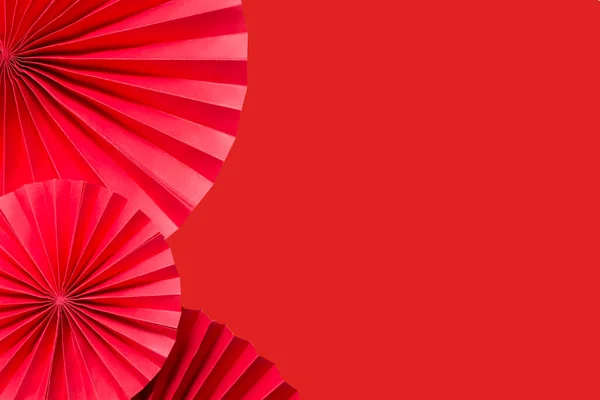 Red paper fans on a red monochrome background with copy space.