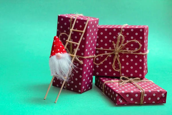 Postcard layout. Heap of gifts on a green background and a gnome on the stairs. Close up copy space — Stockfoto