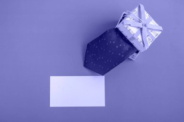 Gift box with tie and card on avery peri background. Holiday gifts close up with copy space