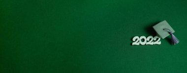 Mezuniyet şapkası ve yeşil arka planda 2022 numara, fotokopi alanı ile kapatın. Tıp eğitimi konsepti. Pankart