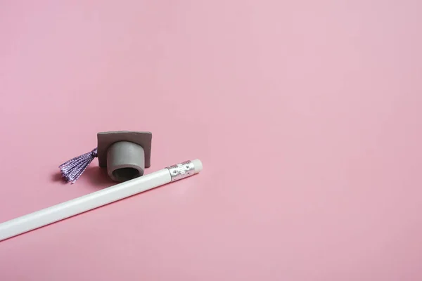 Weißer Bleistift mit Graduierungshut auf rosa Hintergrund Nahaufnahme mit Kopierraum. Bildungskonzept — Stockfoto