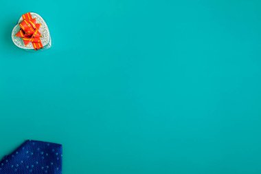 Turkuaz arka planda kravat olan bir hediye kutusu. Tatil hediyeleri kopya alanı ile kapanır
