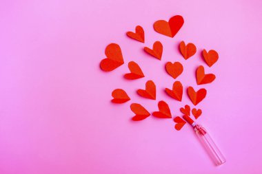 Kırmızı kağıt kalpler şişeden uçuyor. Valentine pembe arkaplanda kopyalama alanı ile