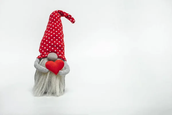 白い背景に孤立した彼の手の中に赤いハートを持つ赤い帽子のドワーフ バレンタインデーのアイデア ロイヤリティフリーのストック写真