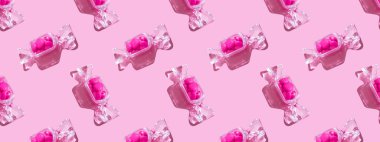 Şeffaf şeker şeklindeki kutuda tatlı kalp lolipopları ve pembe arka planda sert gölgeli fotokopi alanı var. Sevgililer Günü konsepti, anneler günü. Pankart. Desen