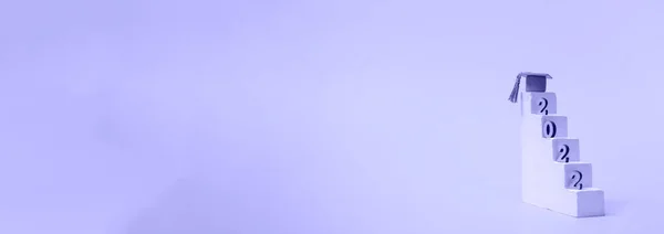 Çok basit bir eğitim kavramı. Mezuniyet 2022. Mezuniyet şapkası ve ahşap numaralarla podyum basamakları