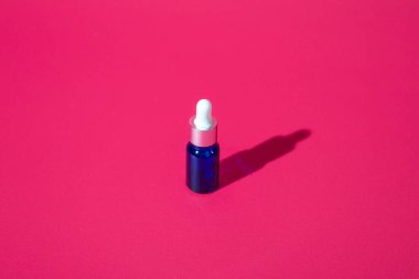 Kozmetik şişe modeli pembe arka planda sert gölgeli kozmetik ürünleri, kopyalama alanını kapat