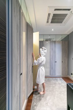 Bornozlu bir kadın gardırop açıyor.