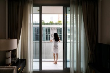 Kadın manzarayı seyretmek için balkonun dışında durdu..