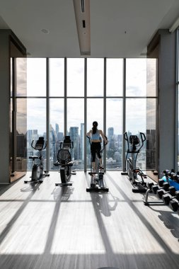 Spor salonunda egzersiz yapan güzel bir kadının arka görüntüsü.