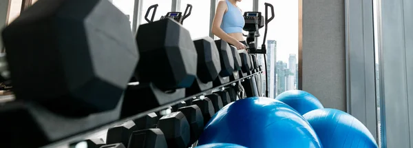 woman wearing sports clothes weighing dumbbells in hands during workout in gym