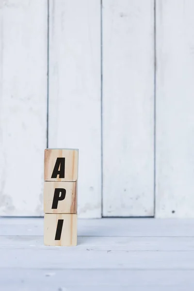 Conceito api escrito em cubos ou blocos de madeira, sobre fundo de madeira branco. — Fotografia de Stock