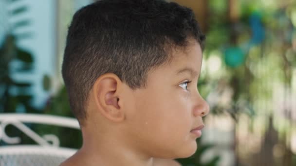 Child looking at camera smiling, child outdoors. — Video