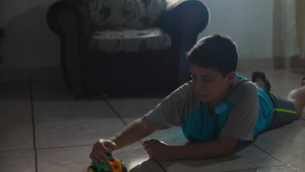 Child playing with a cart on the floor, lying on the floor in the house. — Vídeo de stock