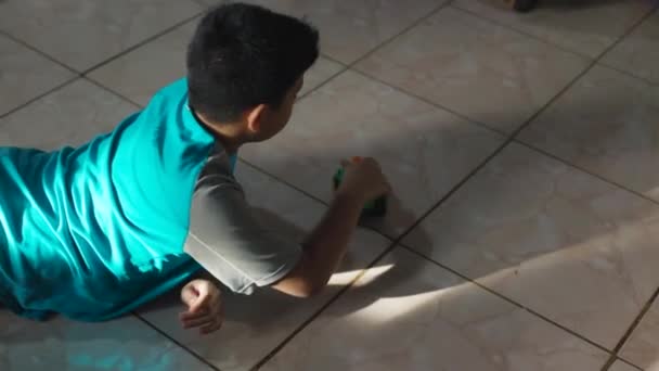 Child playing with a cart on the floor, lying on the floor in the house. — Stockvideo