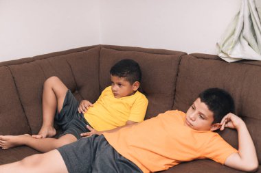 İki çocuk çikolata sandalyesinde oturmuş televizyon seyrediyor.