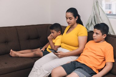 Çikolata koltukta çocuklarının oturduğu cep telefonuna bakıyor.