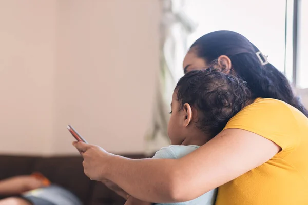 mom looking at the cell phone with her child