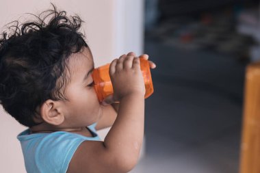 Evin dışında turuncu bir bardakta su iç.