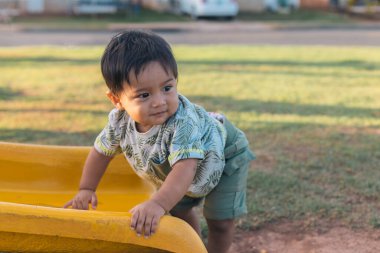 Bebek parkın kaydırağında oynuyor.