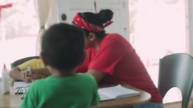 Anne, çocuklarıyla birlikte evdeki masada resim yapıyor..