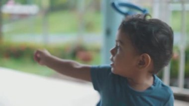 Üç tekerlekli bisikletinin üzerinde oturan bebek arkasını gösteriyor..