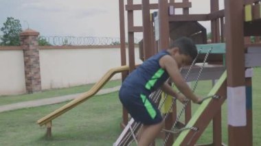 Latin çocuk park oyununda engelleri tırmanıyor.
