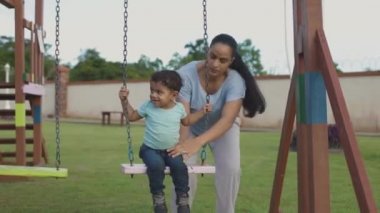 Anne çocuğunu salıncakta sallıyor..