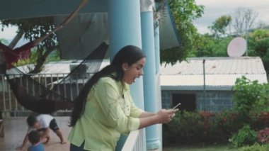 Latin bir kadın cep telefonunda yazarken şaşırdı, çocuklar yerde oynuyordu, orta boy..