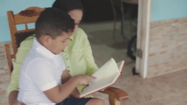 Latynoska Rodzina Mama Czytająca Synowi Czerwoną Książkę Siedząca Bujanym Krześle — Wideo stockowe