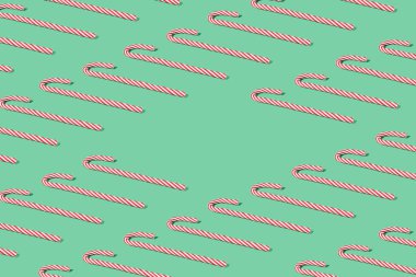 Kırmızı Noel bastonlarıyla yaratılmış yaratıcı desen. Kopyalama alanı olan minimal nane yeşili yeni yıl partisi arka planı.