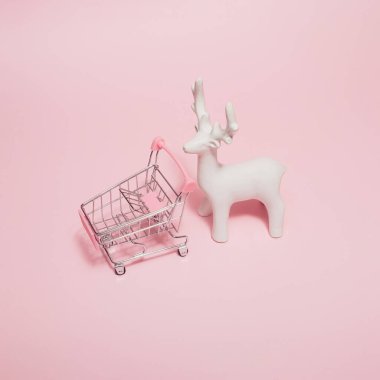 Minimum pastel pembe Noel ya da alışveriş arabası ve beyaz ren geyiği süsüyle yapılan yeni yıl kompozisyonu. Yaratıcı kış konsepti.