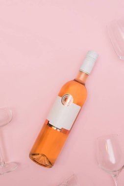 Zarif bir gül şarabı şişesi ve pastel pembe arka planda gözlük. Kopya alanı olan modern Sevgililer Günü konsepti.