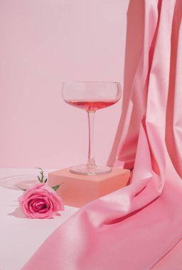 Romantik pastel pembe sevgililer günü kompozisyonu şarap kadehleri, saten perdeler ve gül çiçekleri. Modern estetik.