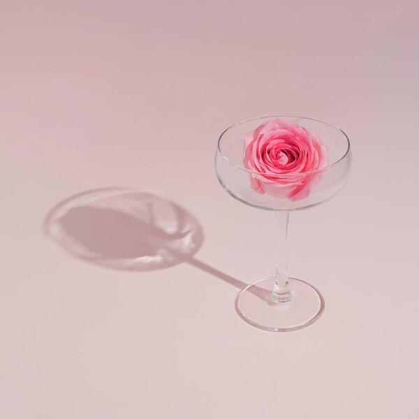 Romantic pink rose and wine glass on pastel background. Minimal modern Valentine party concept.