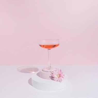 Parlak pembe çiçek ve şarap kadehiyle minimum pastel parti konsepti. Modern bahar ya da yaz estetiği.