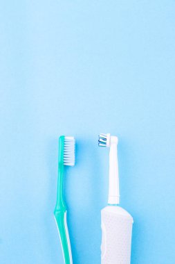 El fırçası elektrikli diş fırçasına karşı, mavi arkaplan, kopyalama alanı, dikey