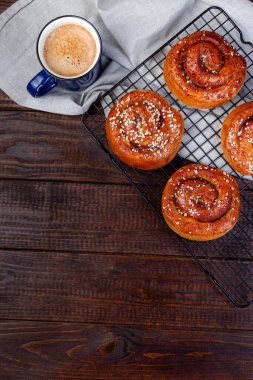 İsveç tarçınlı çörekler bir fincan kahve, ahşap arka plan, dikey, kopyalama alanı