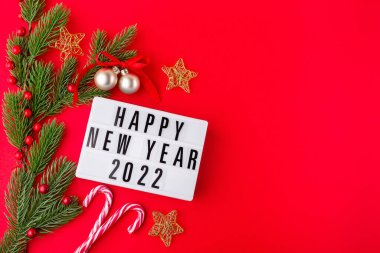 Çam dalları, yıldızlar, şeker kamışı, neşeli toplar ve ışık kutusuyla kırmızı arka planda, yatay, fotokopi alanı, üst manzara. Mutlu yıllar konsepti