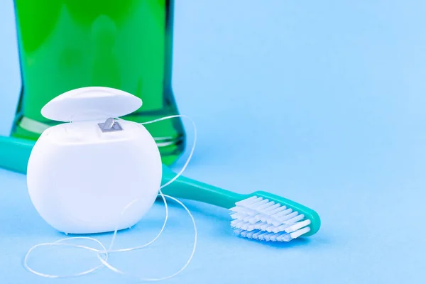 Tandtråd, tandborste och munvatten på blå bakgrund. Tandvård och munhygienprodukter — Stockfoto
