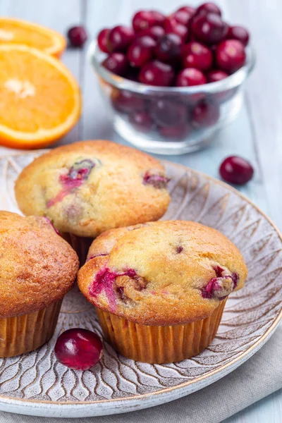 Cranberry orange muffins on wooden plate, vertical