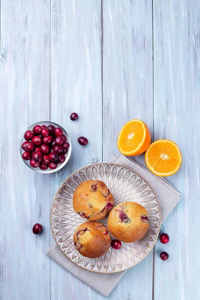 Homemade cranberry orange muffins on wooden plate, vertical, top view, copy space