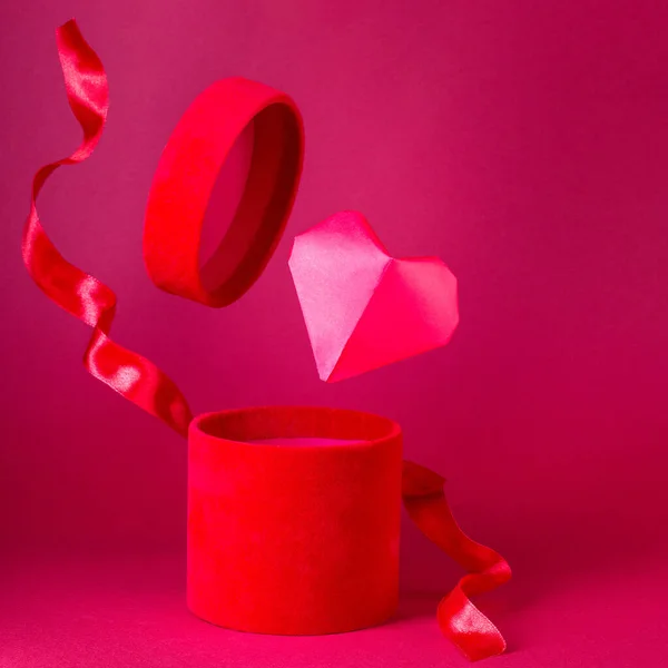 Red velvet box with red silk ribbon, big red paper heart flying from box, square format — стоковое фото