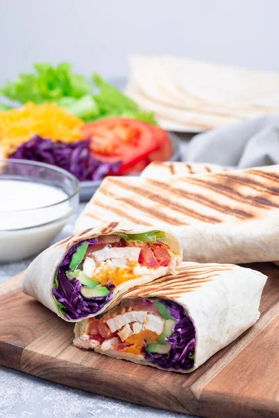 Grilled chicken wraps with red cabbage, avocado, tomato, lettuce, cheddar cheese, on wooden board — Fotografie, imagine de stoc