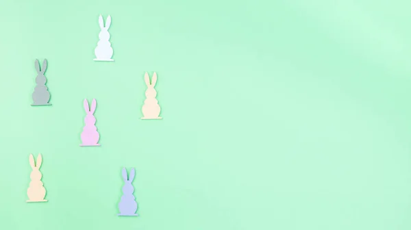 Texture carta verde con figure di coniglietto di Pasqua in legno colorato, orizzontale, spazio copia — Foto Stock