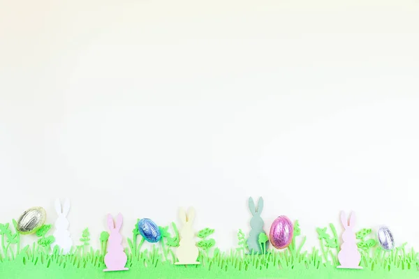 Textura de papel amarelo com grama de feltro verde, coelho e ovos coloridos, fundo de Páscoa, horizontal, espaço de cópia — Fotografia de Stock