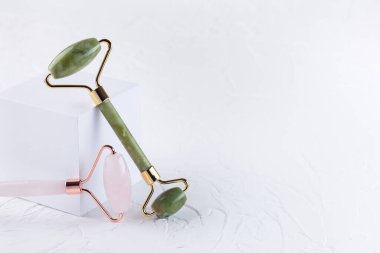 Beyaz arka plan, yatay, kopyalama alanı üzerinde beyaz küp podyumu yakınında gül kuvars kristali ve yeşim yüz silindiri