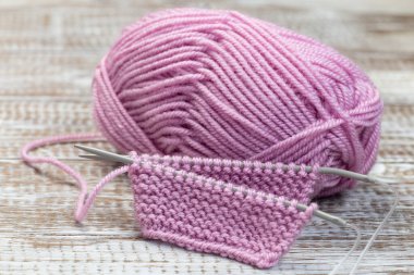 İğneli örgü ve ahşap arka planda pembe iplik kesesi, yatay