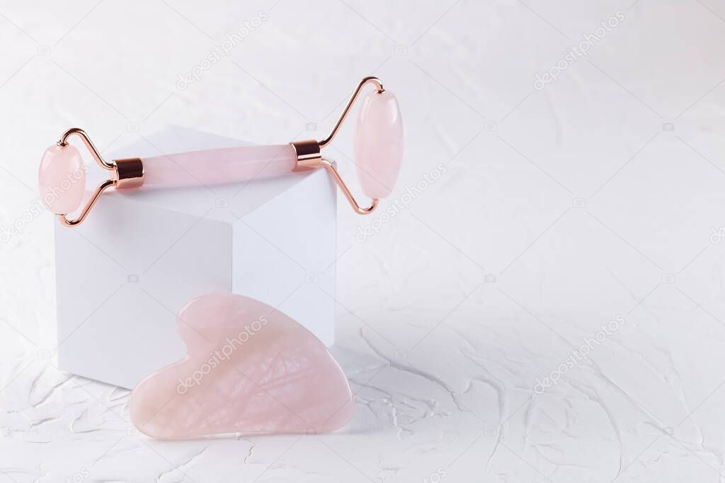 Rose quartz crystal facial roller and massage tool Gua sha on a white background, horizontal